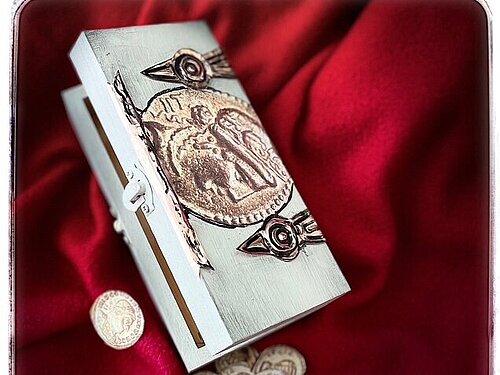 römische Schatzkiste auf ein rotes Tuch mit Geldmünzen aus Holz